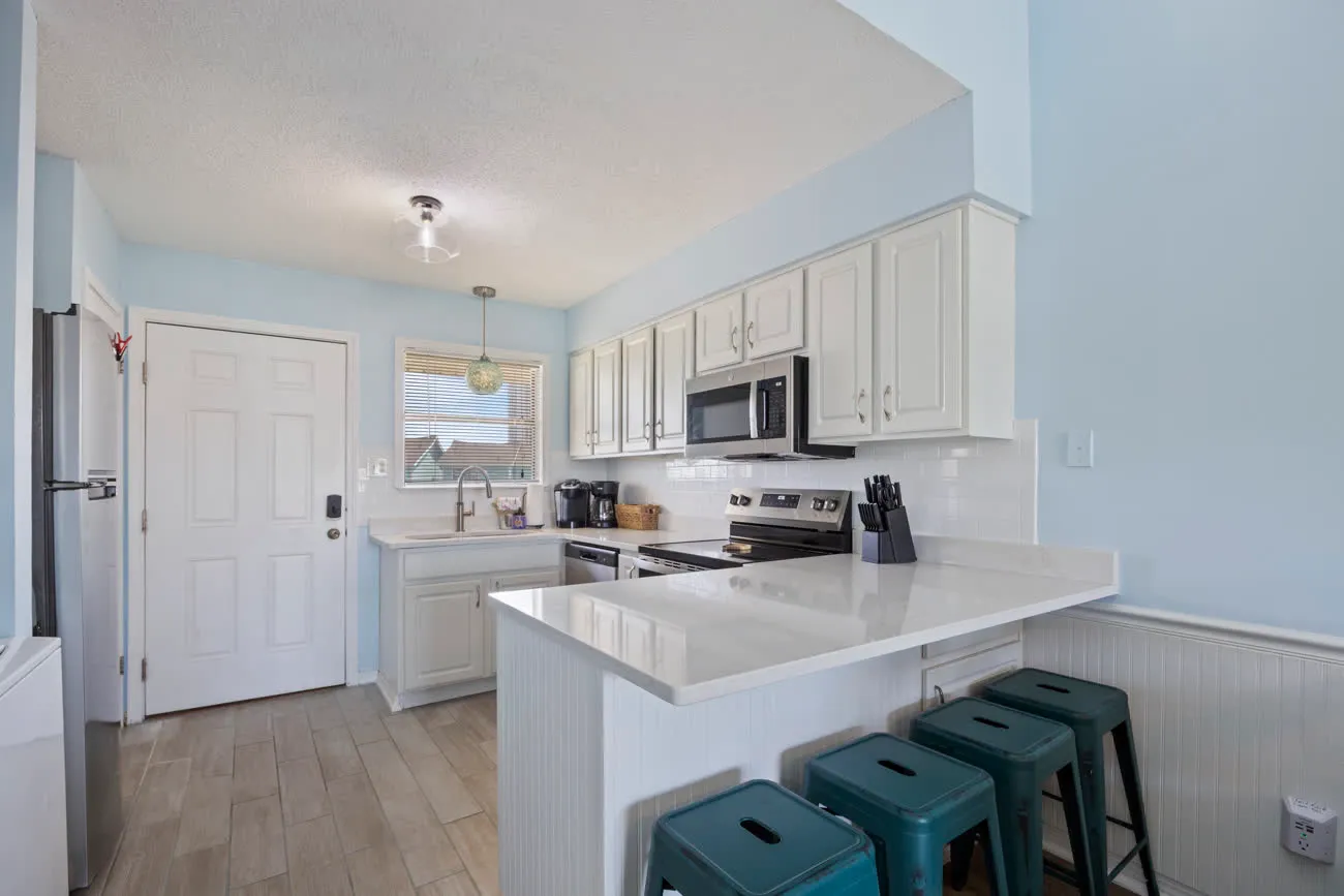 Kitchen entry with door, breakfast bar, and stools