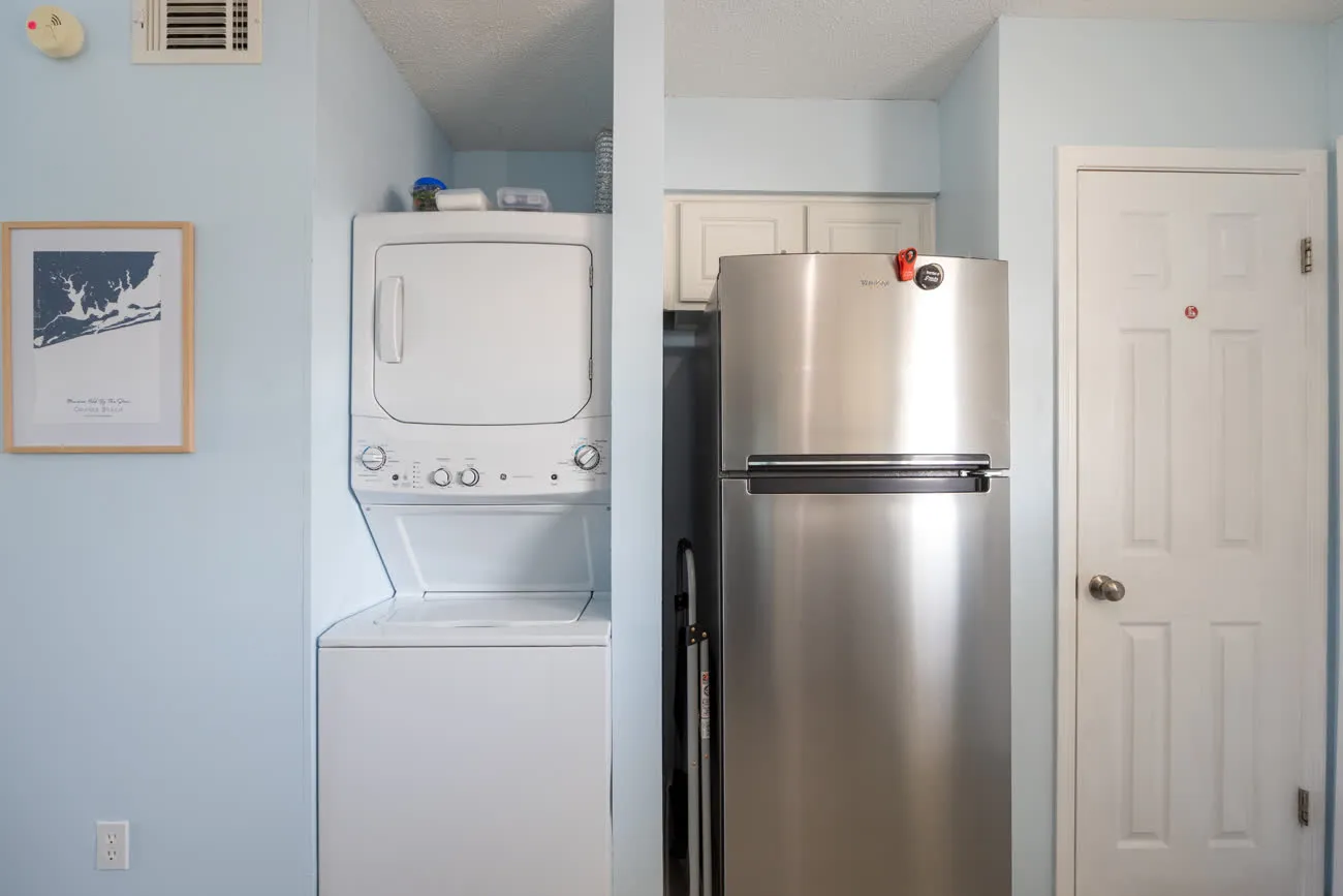 Stacked in-unit washer and dryer beside the refrigerator