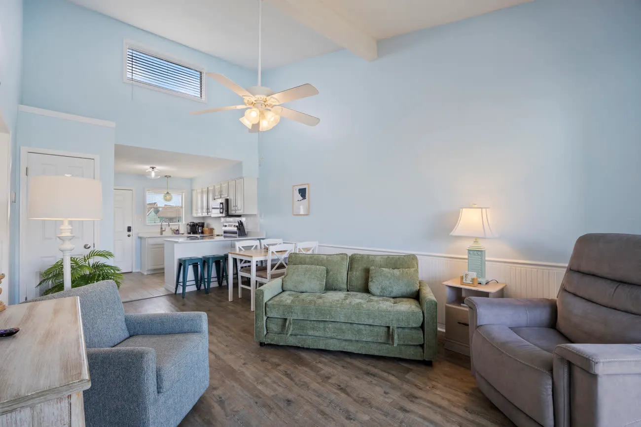 Living room from far corner with sofa, chairs, and view to kitchen