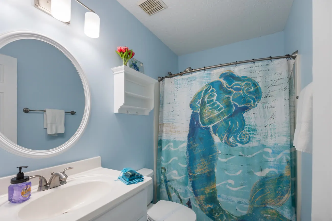 Hall bathroom vanity with round mirror and mermaid shower curtain