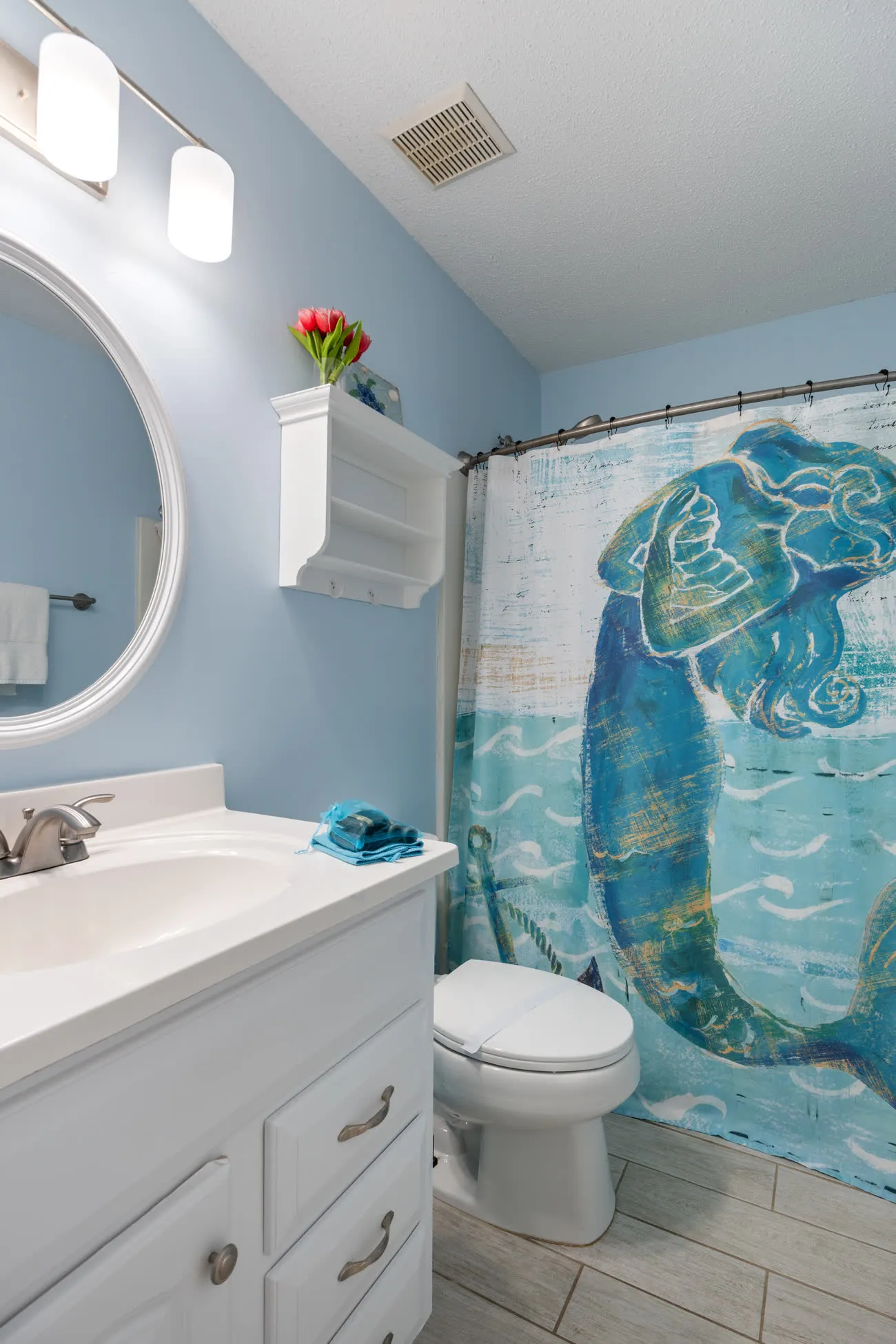 Hall bathroom toilet and sink with mermaid shower curtain