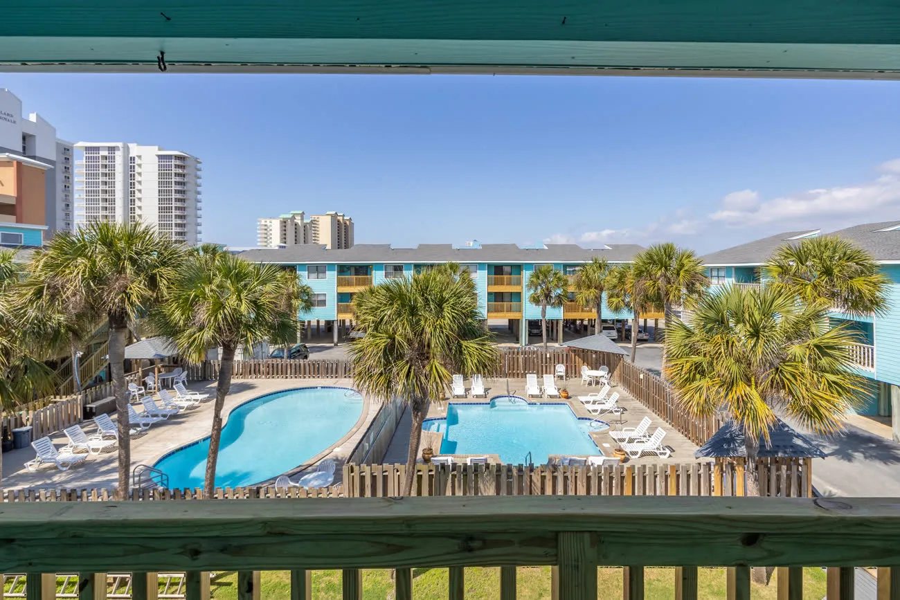 Both pools viewed from balcony through wood railing