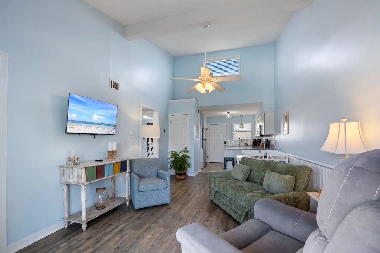 Wide living room with TV, sofa, and view back to entry and kitchen